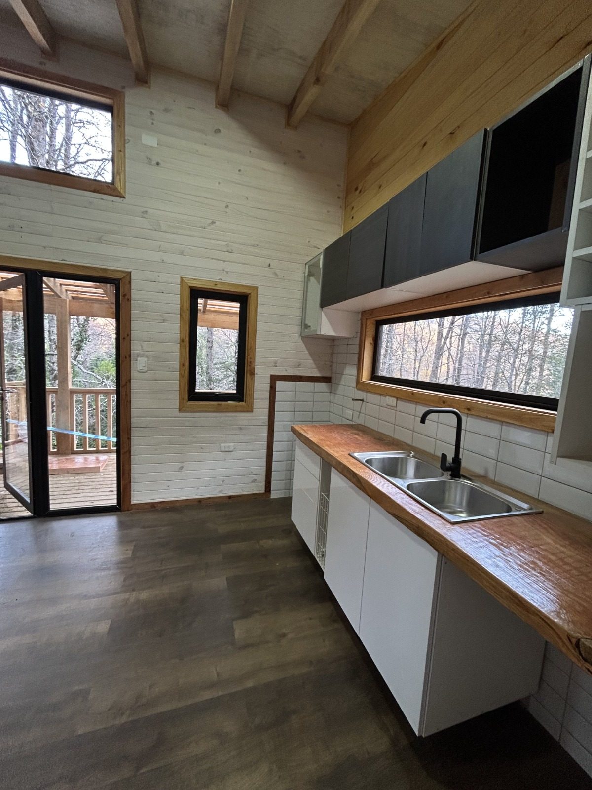 Cocina equipada y amoblada, con ventanas largas hacia el bosque